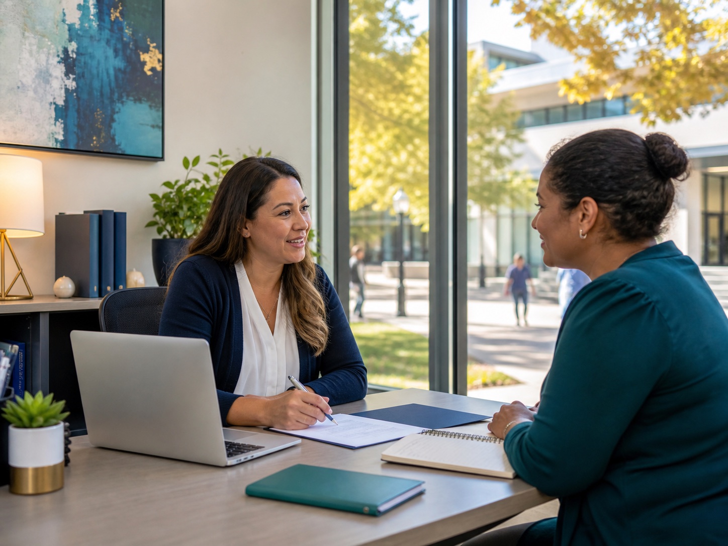 Two adults meeting with a laptop and paperwork, representing one-on-one support for navigating digital systems.